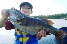 Young boy holds a monster summer smallmouth.