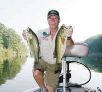 Famous outdoors sports pro and media member Ray Simms with a pair of bass caught by crossing over.