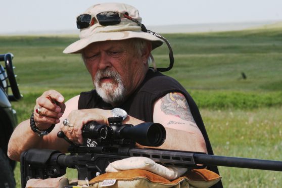 Man loading single round into the breech of a scoped Brezny Howa Chassis rifle.