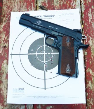 The M1911 with a shot target displaying nearly every shot within the middle 4 inches, with several in the 2-inch bull’s-eye.