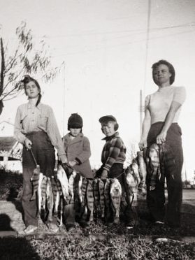 Black and white photo of two women and two children--one is Rick Clunn--holding a stringer of fish.