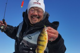 Ted Takasaki, professional walleye angler and author, displays a freshly caught fish found lurking under the ice.