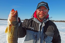 Ice fisherman displaying a large walleye caught from under an icy lake. Electronics help big lakes fish small.